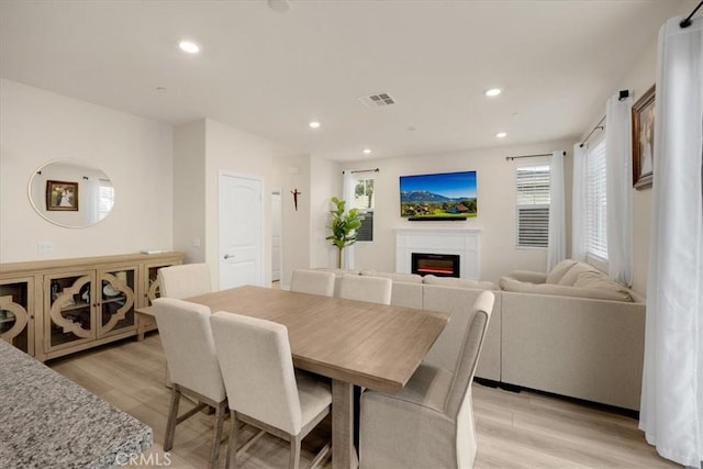 dining space with recessed lighting, light wood-type flooring, visible vents, and a glass covered fireplace