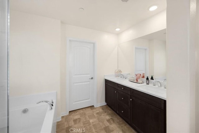 full bath featuring a sink, baseboards, a garden tub, and double vanity