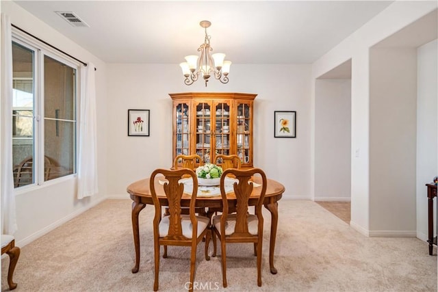 dining space featuring a chandelier, visible vents, light colored carpet, and baseboards