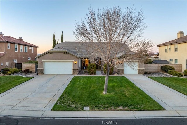 view of front facade with a front yard, fence, driveway, an attached garage, and stucco siding