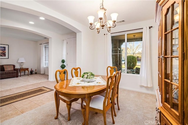 dining space featuring visible vents, arched walkways, light tile patterned floors, baseboards, and a chandelier