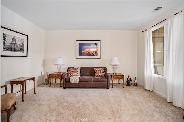 living area with plenty of natural light, light colored carpet, baseboards, and visible vents