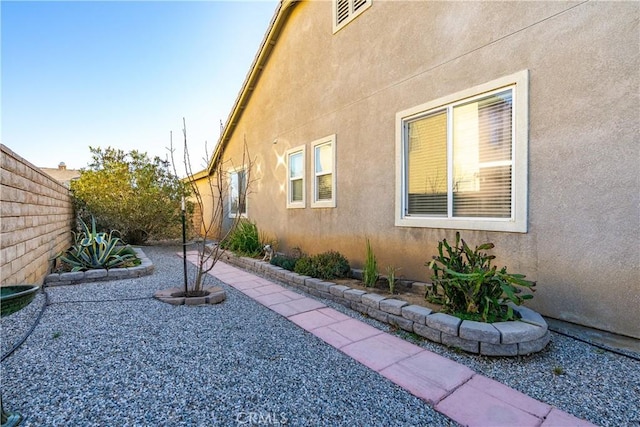 view of side of home featuring a patio area, stucco siding, and fence