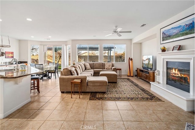 living room featuring a glass covered fireplace, light tile patterned floors, visible vents, and a wealth of natural light