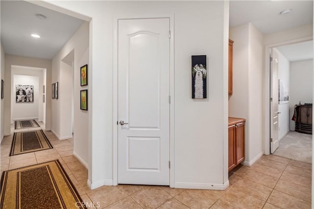 hall featuring light tile patterned flooring and baseboards