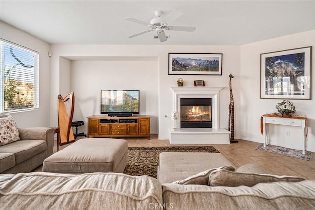 living room with tile patterned floors, a glass covered fireplace, and ceiling fan