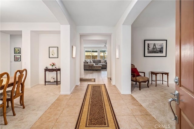 foyer entrance with arched walkways, light colored carpet, and light tile patterned flooring