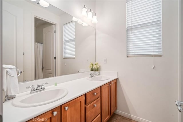 full bath featuring double vanity, tile patterned flooring, baseboards, and a sink