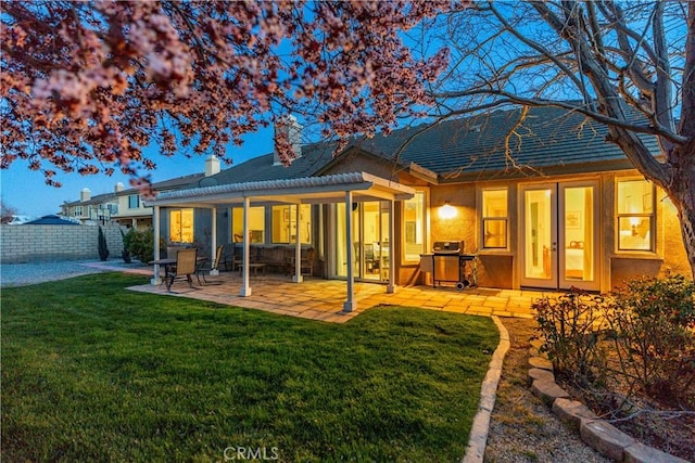 rear view of house with a patio, fence, a lawn, and a chimney