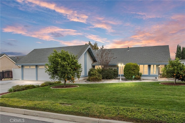 view of front facade featuring a garage, a front lawn, driveway, and a shingled roof