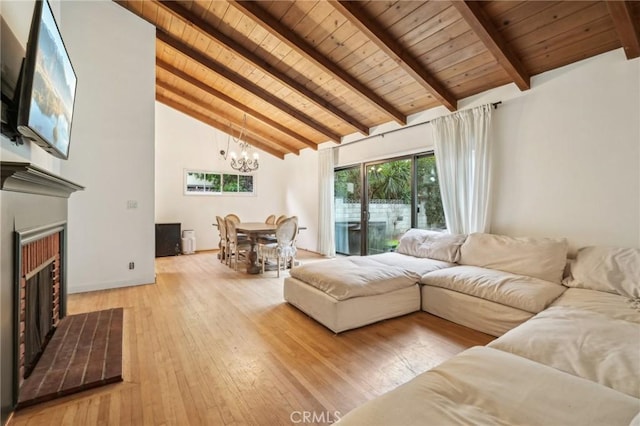 living area with wood ceiling, an inviting chandelier, beamed ceiling, and a brick fireplace