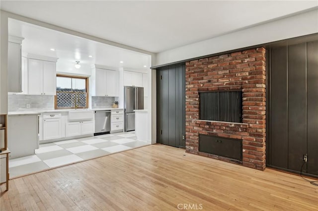 kitchen featuring tasteful backsplash, stainless steel appliances, light wood-style floors, light countertops, and white cabinetry
