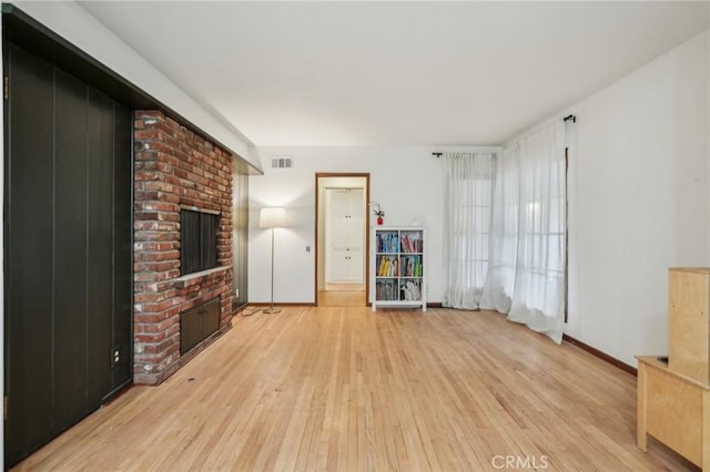 unfurnished living room featuring visible vents, a fireplace, light wood-style floors, and baseboards