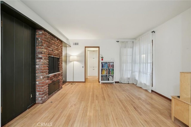 unfurnished living room featuring a fireplace, visible vents, light wood finished floors, and baseboards