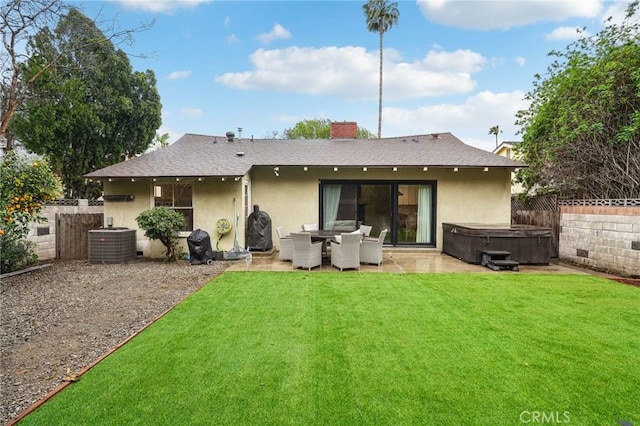 back of property with stucco siding, a shingled roof, a hot tub, a patio, and central AC unit
