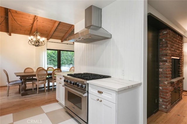 kitchen with wooden ceiling, stainless steel stove, beamed ceiling, white cabinetry, and wall chimney exhaust hood