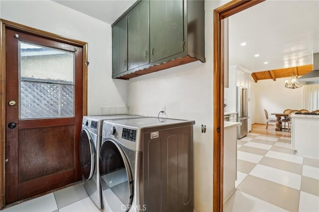 clothes washing area with a chandelier, light floors, cabinet space, and washer and clothes dryer
