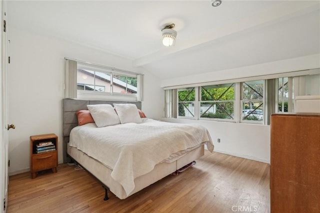 bedroom with lofted ceiling with beams, baseboards, and wood finished floors