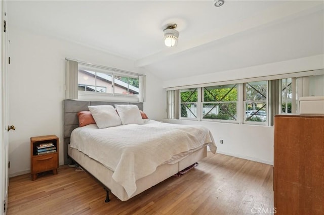 bedroom with wood finished floors, lofted ceiling with beams, and baseboards