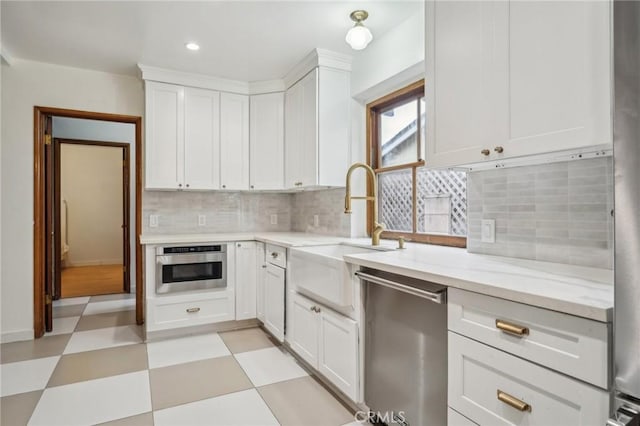 kitchen with light stone counters, white cabinetry, appliances with stainless steel finishes, decorative backsplash, and light floors