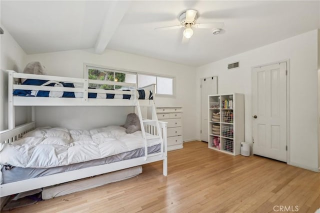 bedroom featuring ceiling fan, visible vents, wood finished floors, and vaulted ceiling with beams