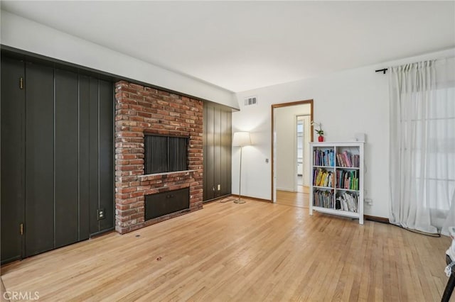 unfurnished living room with a fireplace, visible vents, light wood-type flooring, and baseboards