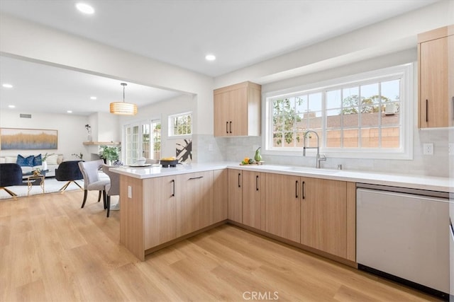 kitchen featuring light brown cabinetry, light wood finished floors, dishwasher, and a peninsula