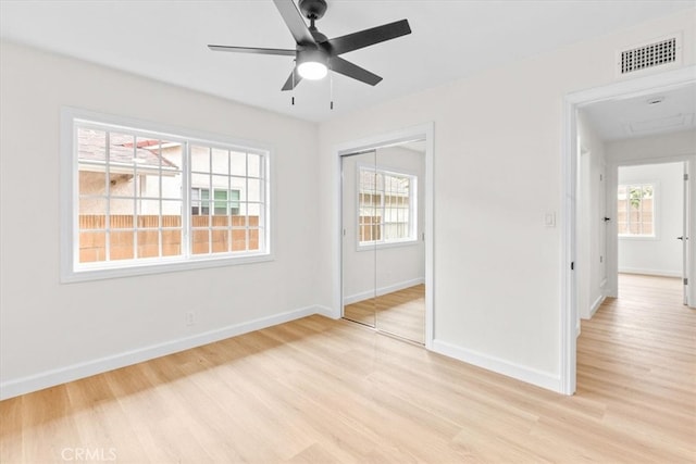 unfurnished room featuring a wealth of natural light, visible vents, light wood-type flooring, and baseboards