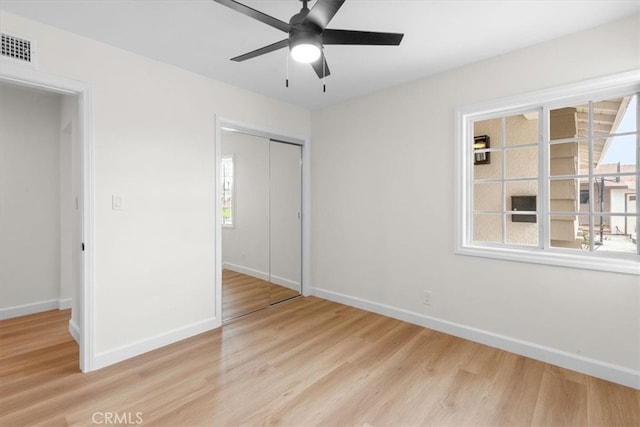 unfurnished bedroom with light wood finished floors, visible vents, baseboards, multiple windows, and a closet