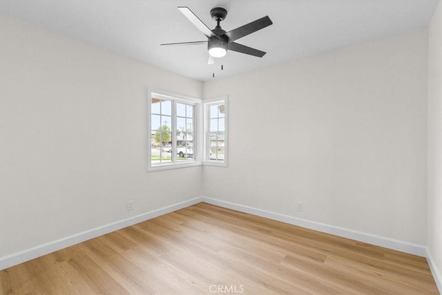 spare room with baseboards, a ceiling fan, and light wood finished floors