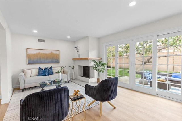 living room featuring a fireplace, recessed lighting, wood finished floors, and visible vents