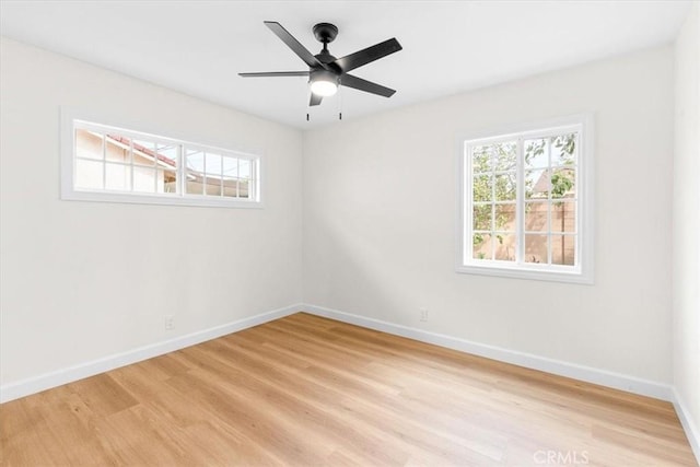 empty room featuring a ceiling fan, light wood-type flooring, and baseboards