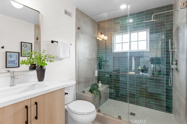 full bathroom with visible vents, a shower stall, toilet, and vanity