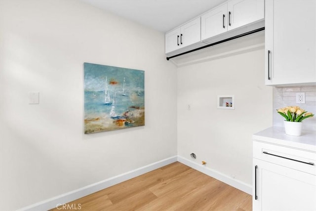 washroom featuring cabinet space, light wood-style flooring, baseboards, and washer hookup