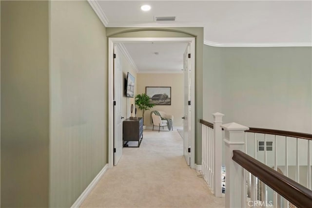 hallway with visible vents, an upstairs landing, carpet, and ornamental molding