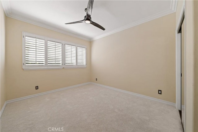 carpeted spare room with a ceiling fan, baseboards, and ornamental molding