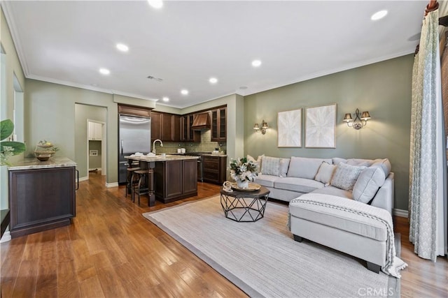 living room with ornamental molding, baseboards, and wood finished floors