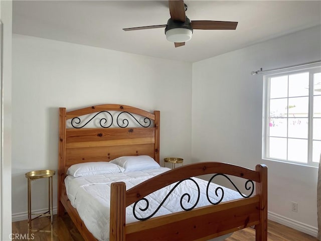 bedroom with a ceiling fan, wood finished floors, and baseboards