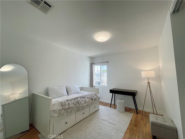 bedroom featuring wood finished floors, visible vents, and baseboards