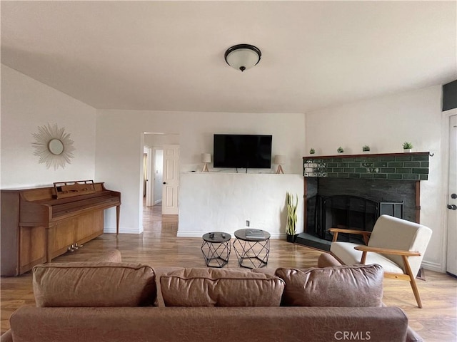 living area with wood finished floors, baseboards, and a tile fireplace