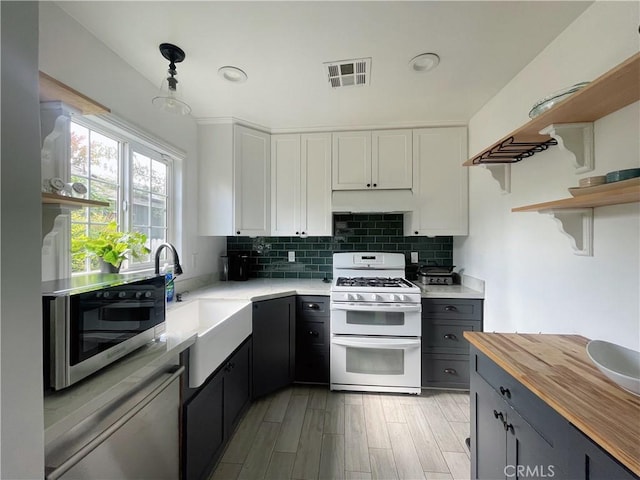 kitchen with decorative backsplash, open shelves, double oven range, and visible vents