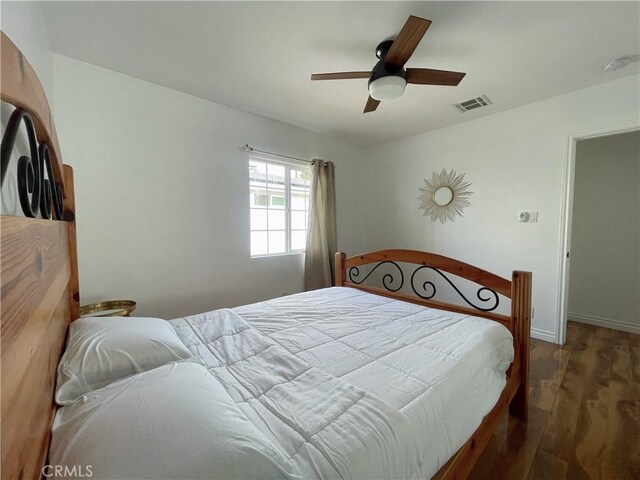 bedroom with visible vents, baseboards, wood finished floors, and a ceiling fan