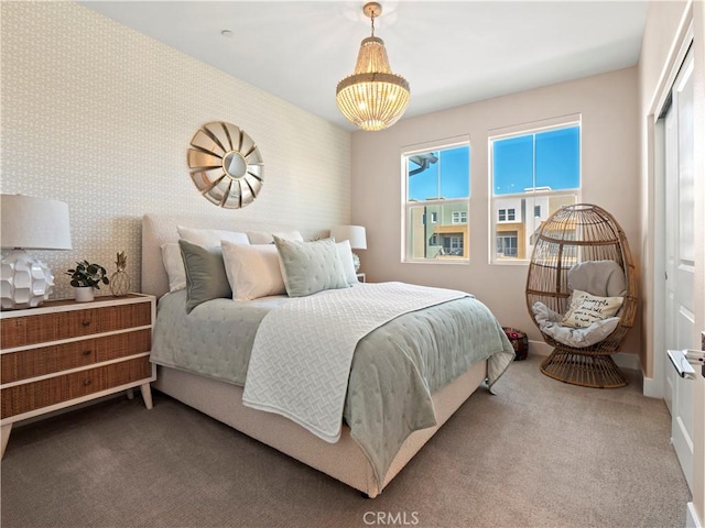 bedroom with wallpapered walls, an accent wall, baseboards, carpet, and a chandelier