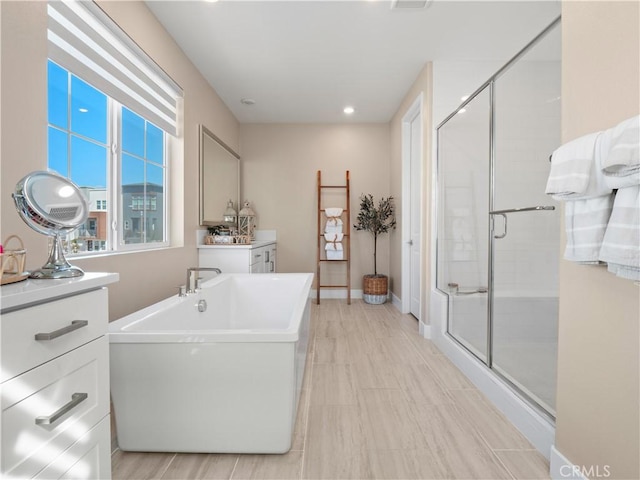 bathroom with a shower stall, baseboards, and a freestanding tub