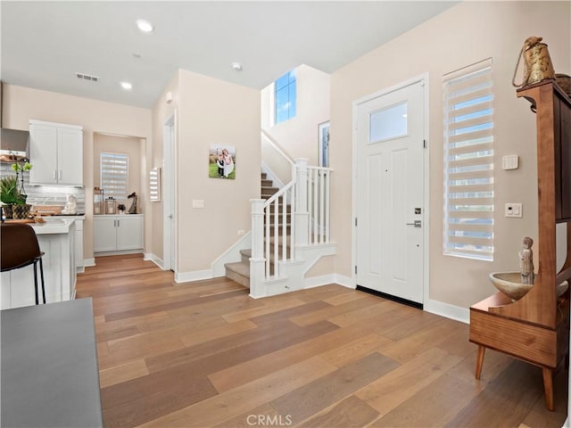 foyer entrance with light wood-type flooring, visible vents, recessed lighting, baseboards, and stairs