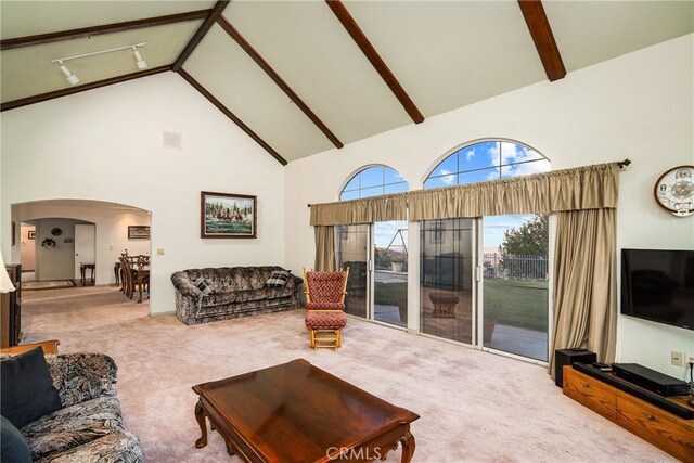 living area with visible vents, carpet floors, high vaulted ceiling, beam ceiling, and arched walkways