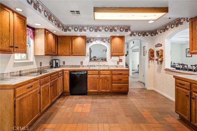 kitchen with visible vents, black appliances, a sink, tile countertops, and wallpapered walls