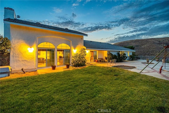 view of front facade featuring a patio area, stucco siding, and a front yard