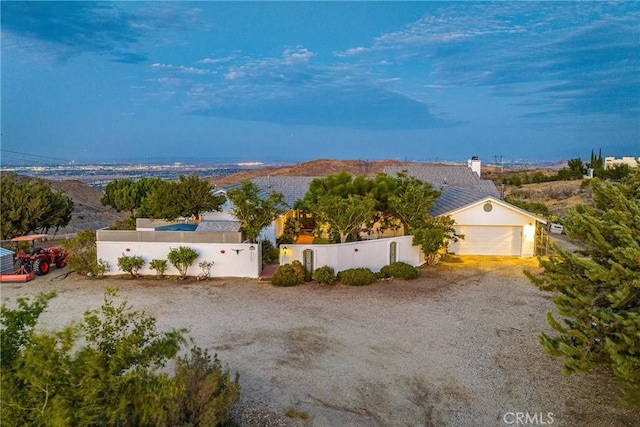 view of front of house featuring a fenced front yard, stucco siding, gravel driveway, and a garage