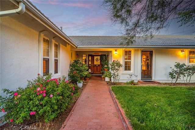 property entrance with stucco siding and a lawn